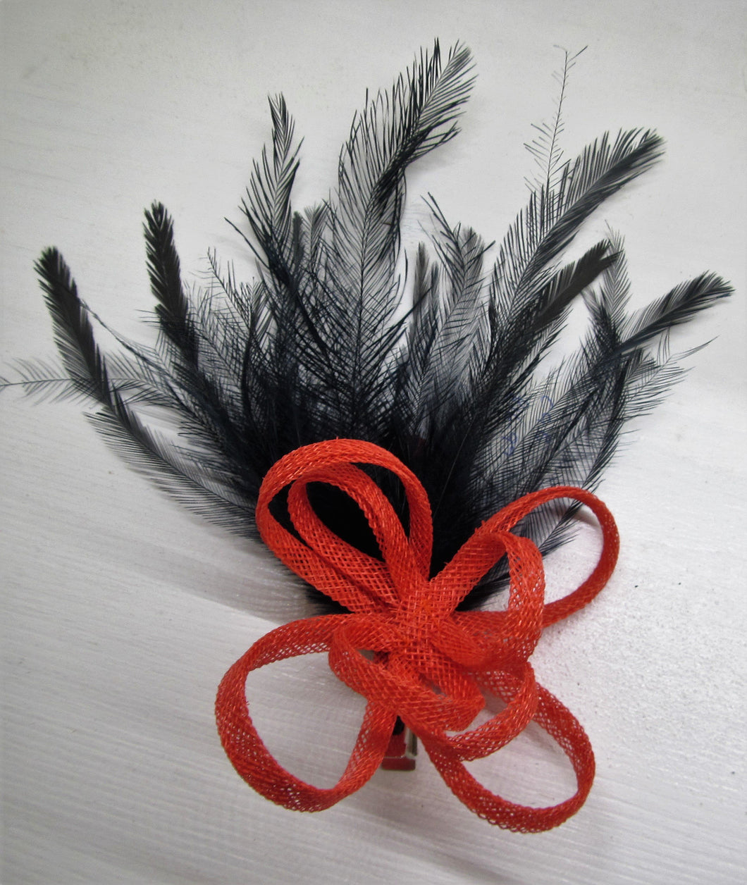 Handcrafted burnt orange bow fascinator with navy blue feathers on a clip