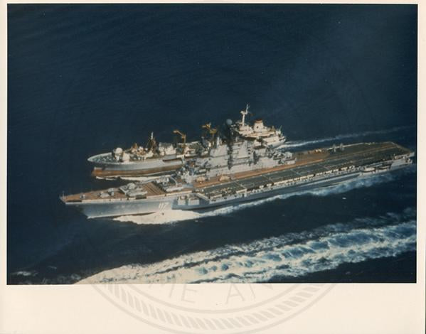 Official U.S. Navy photo of Soviet Kiev class aircraft carrier Minsk underway with an aircraft hovering above the deck.