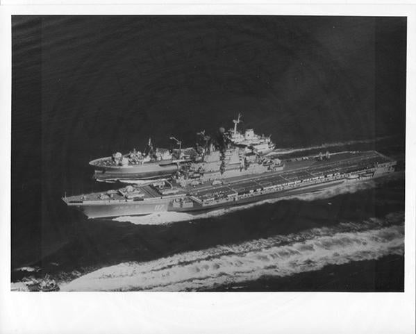 Official U.S. Navy photo of Soviet Kiev class aircraft carrier Minsk underway with an aircraft hovering above the deck.